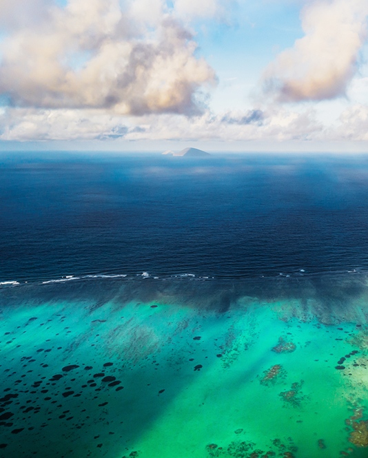 Image of an open blue ocean and puffy white clouds